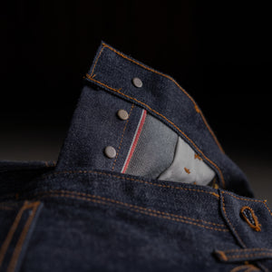 Close-up of a blue denim pocket with stitching details on a dark background