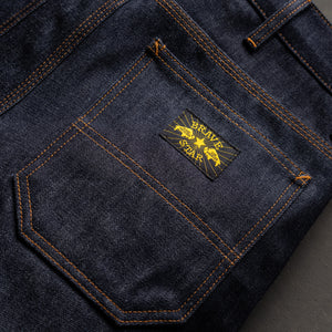 Close-up of a denim pocket with a brand logo on a dark background