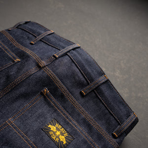 Dark blue denim jeans with a brand logo on a gray background