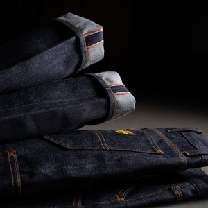 Stack of dark blue jeans on a black background