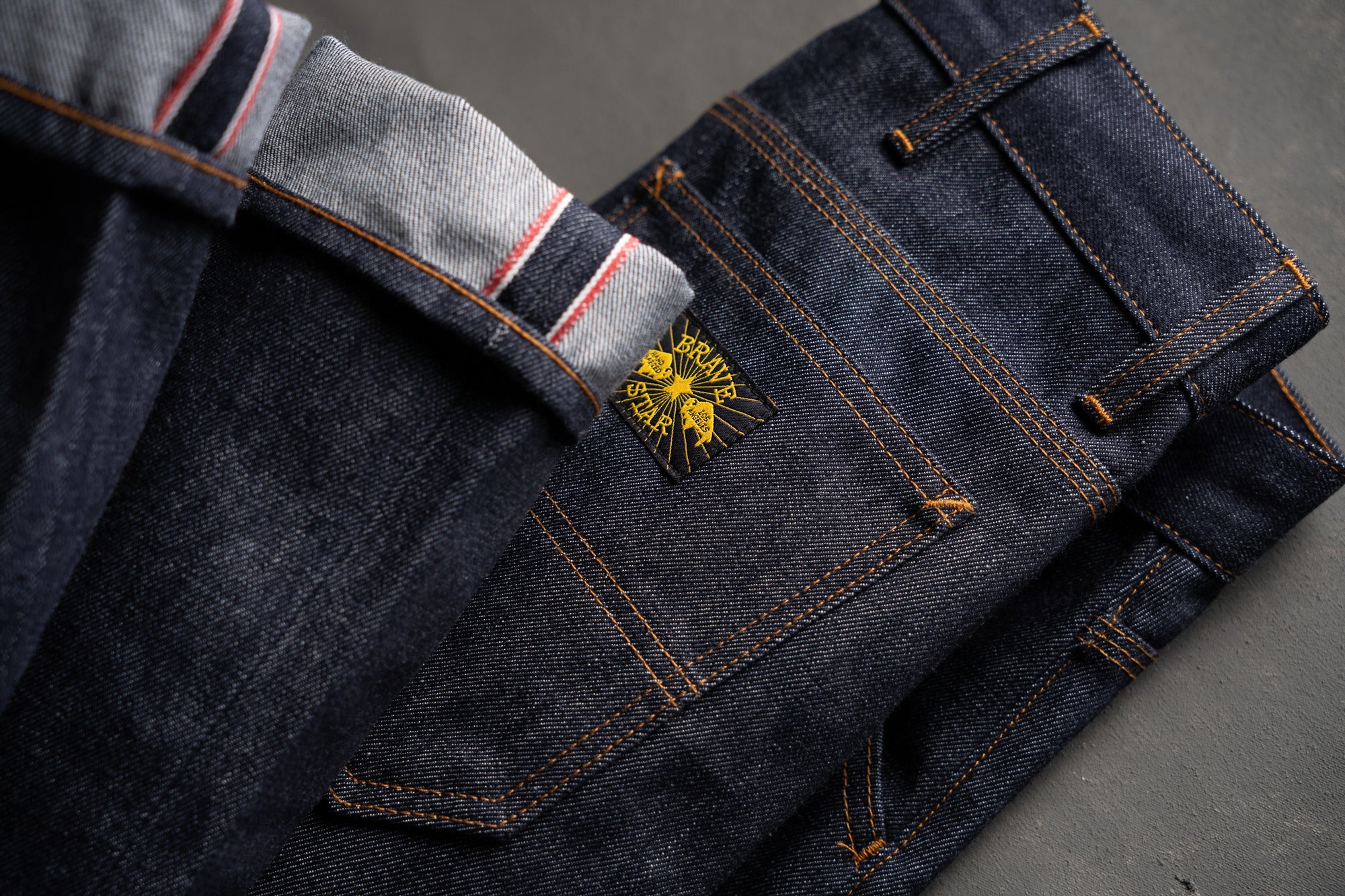 Folded pair of jeans with a brand logo on a gray background