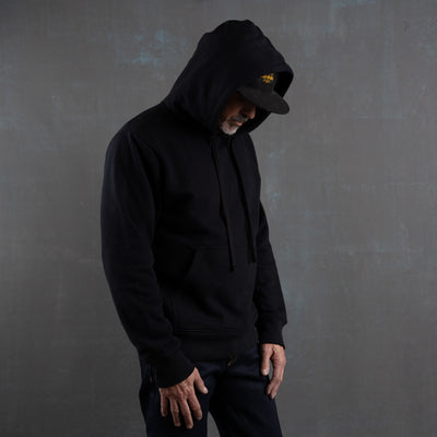 Person wearing a black hoodie against a gray background