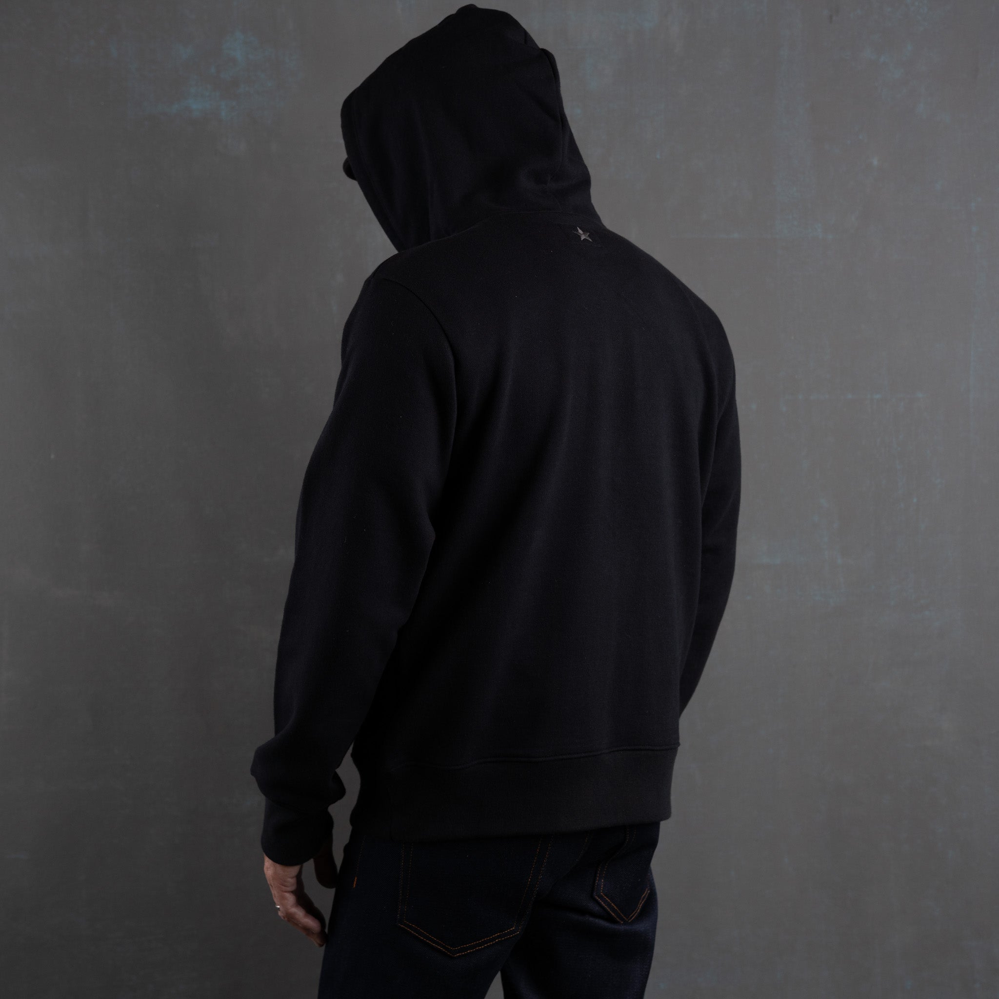 Person wearing a black hoodie against a dark gray background